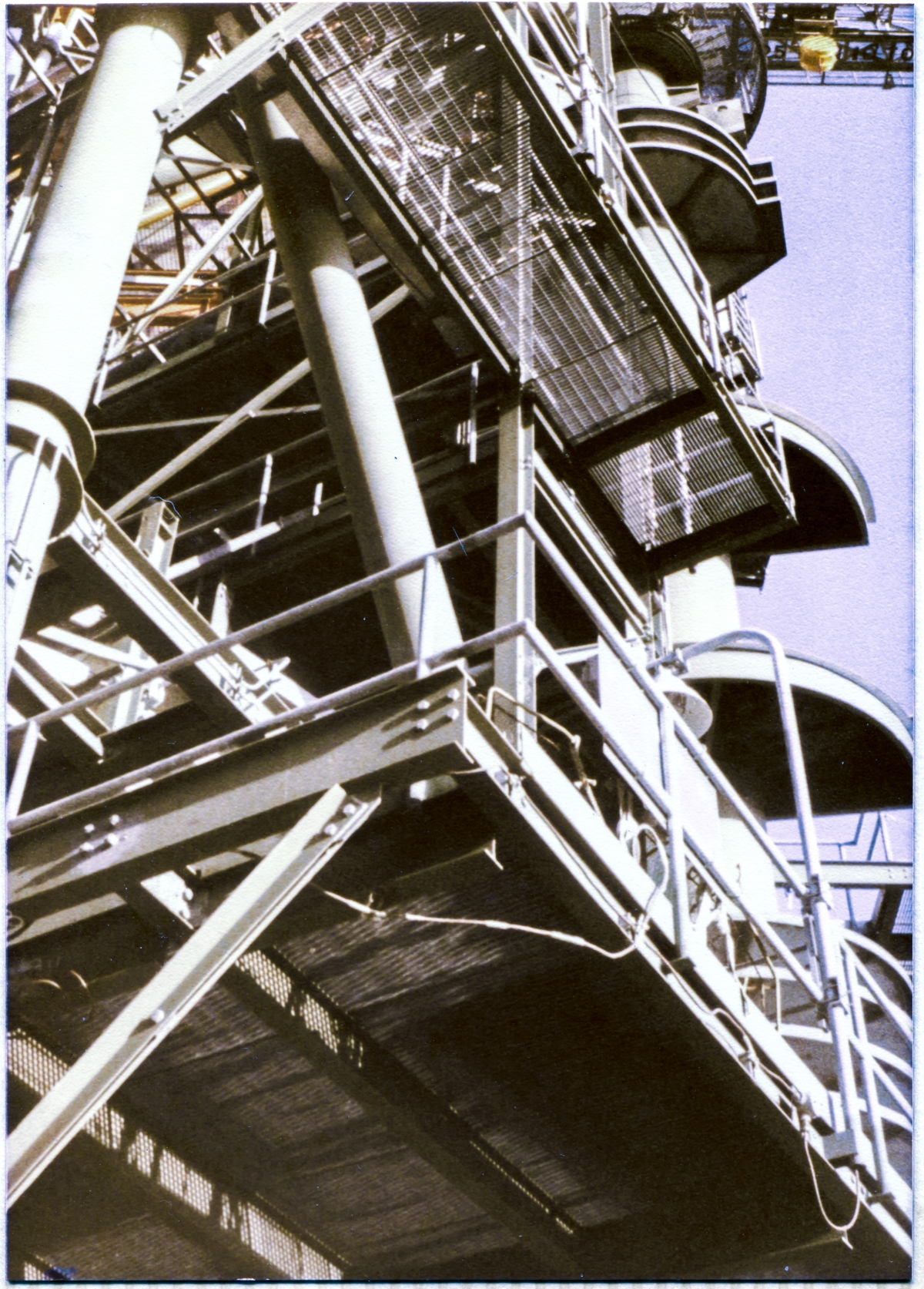 Image 023. From a viewpoint at the front corner of the left Tail Service Mast Access Platform, looking back and steeply upwards, toward the Hinge Column, the platform framing of the face of the Rotating Service Structure between Column Lines 1 and 2, at Launch Complex 39-B, Kennedy Space Center, Florida, takes on a very science-fiction aspect, with the uncanny visual appeal of a gigantic massive thing that cannot possibly be real, but very much so, is. Photo by James MacLaren.